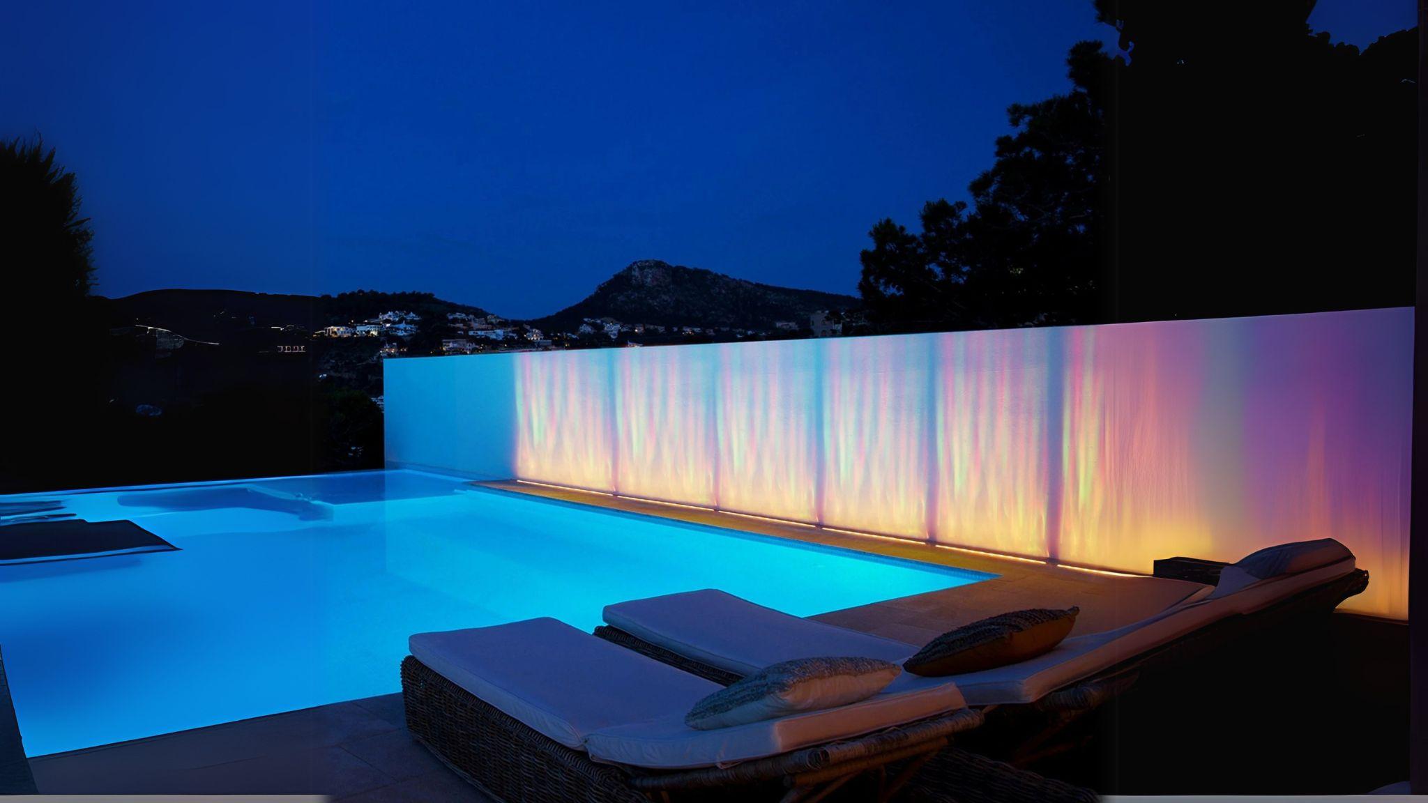 Waterproof Outdoor RGBW Ocean Wave Lights creating vibrant colorful waves along a modern poolside wall at night.