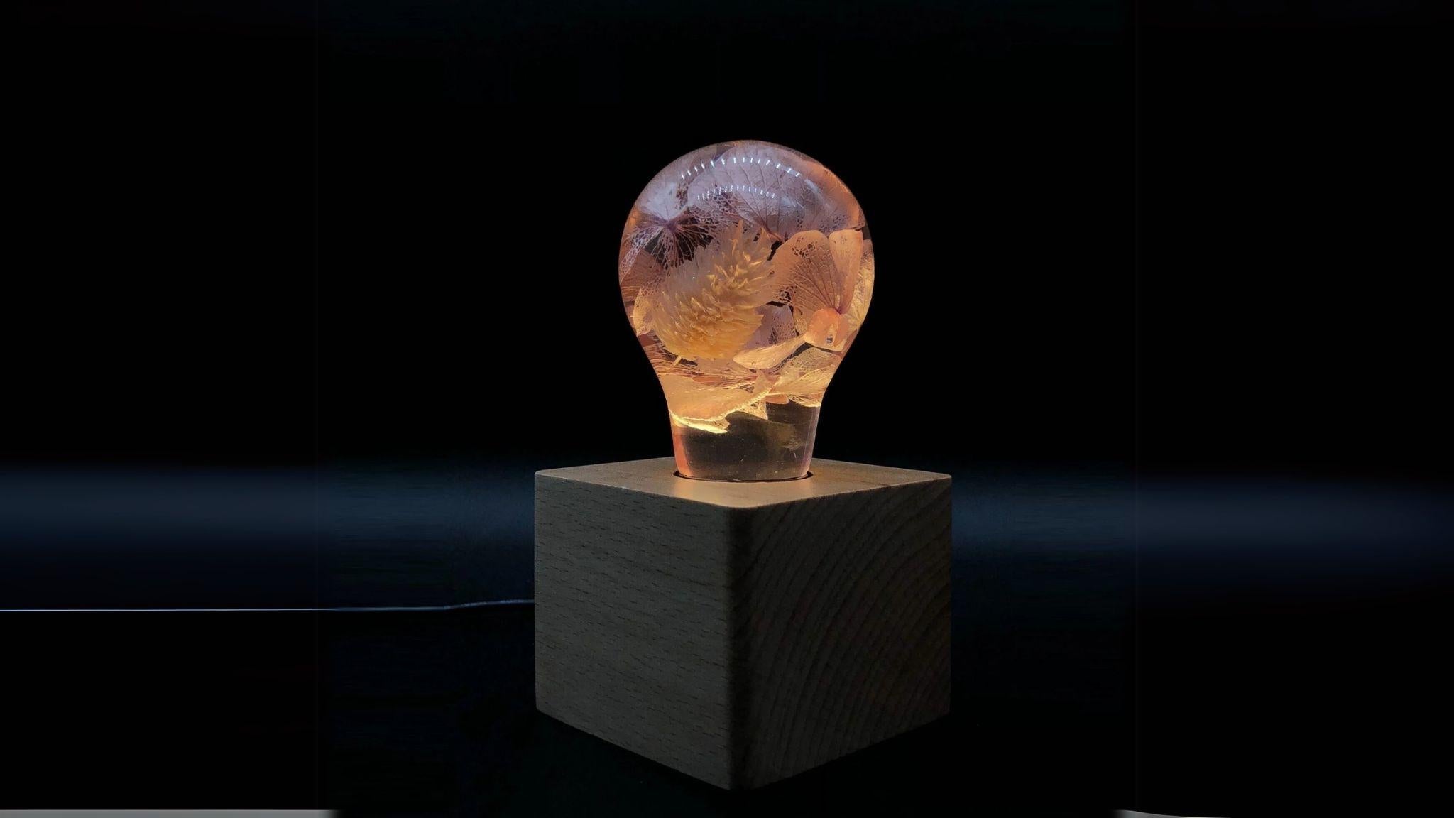 EP Light - Pink Hydrangea eco-resin bulb glowing softly on wooden base, unique handcrafted floral design.