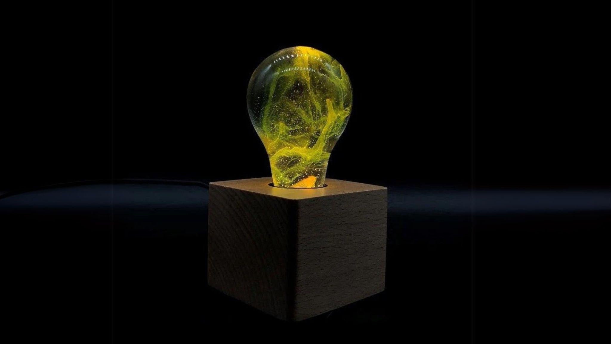 EP Light - Galaxy bulb glowing with yellow galactic swirls on a wooden cube base, eco-friendly and stylish LED light.