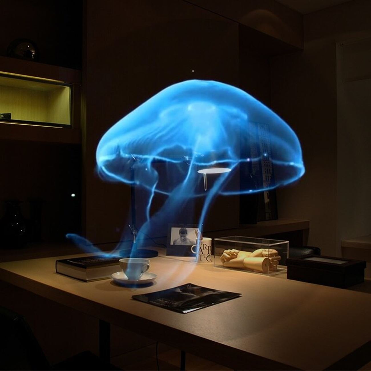 3D Hologram Projection Light displaying a vivid blue jellyfish hologram in a modern office setting.