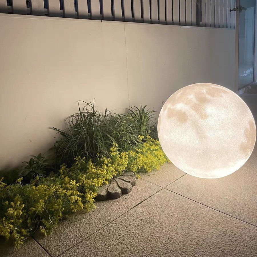 3D Moon Indoor & Outdoor Floor Lamp glowing beside plants, adding warm ambient light for stylish indoor and outdoor decor.