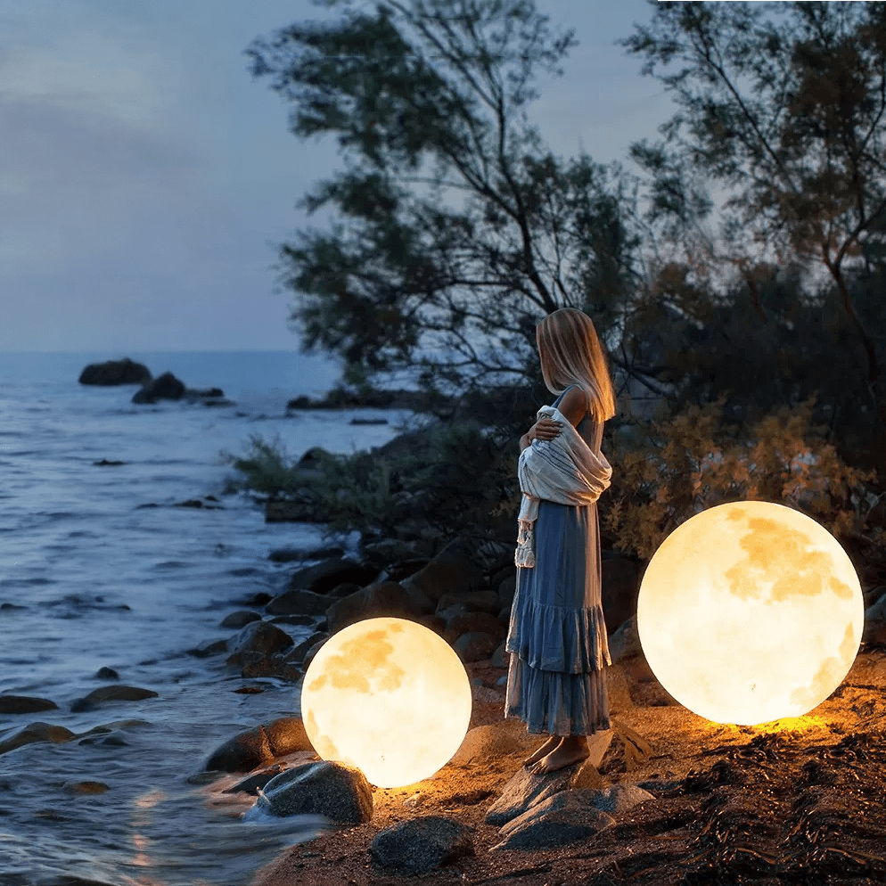 3D Moon Indoor & Outdoor Floor Lamp glowing warmly by the shore, perfect for ambient indoor and outdoor décor.
