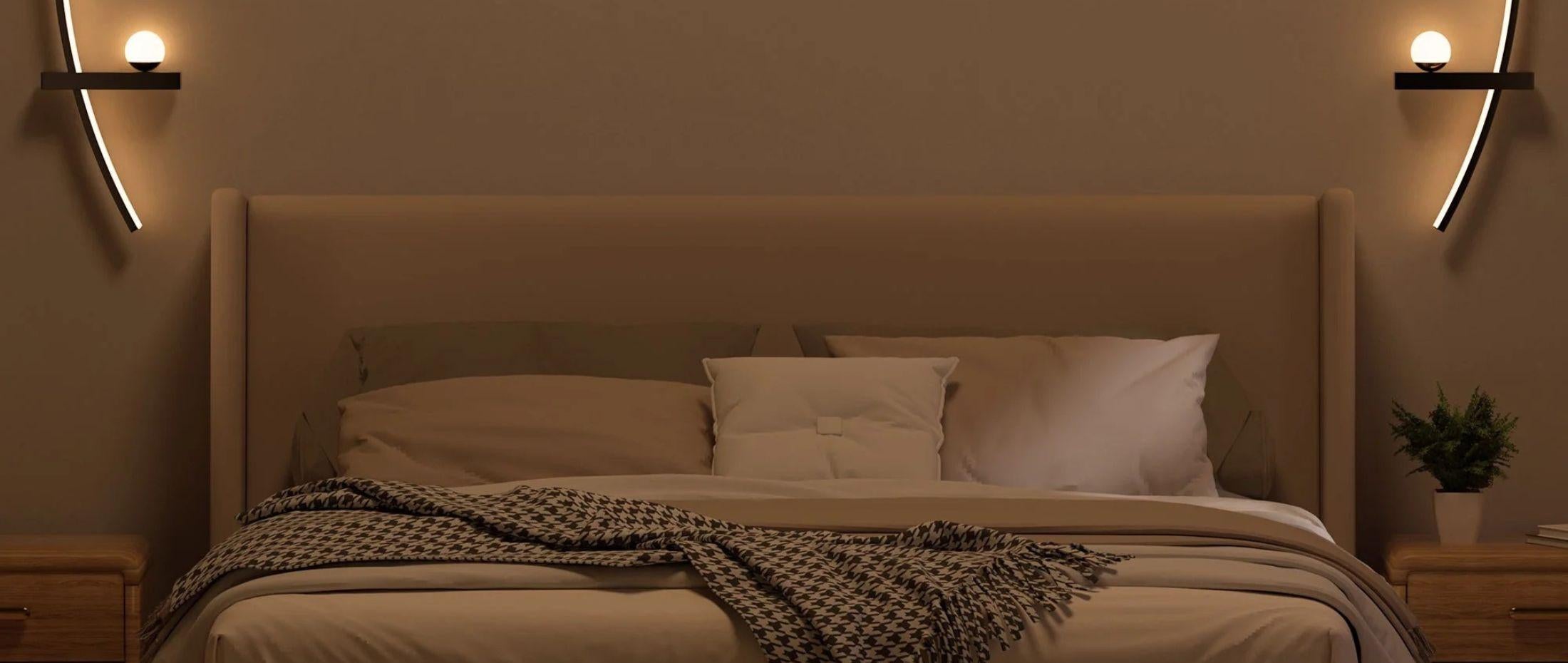 Modern bedroom with neutral bedding and two curved wall sconces with round bulbs mounted above each nightstand.