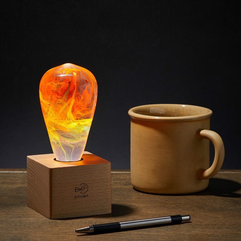 EP Light - Nebula handcrafted LED bulb with unique swirling nebula design on wooden base beside mug and pen.