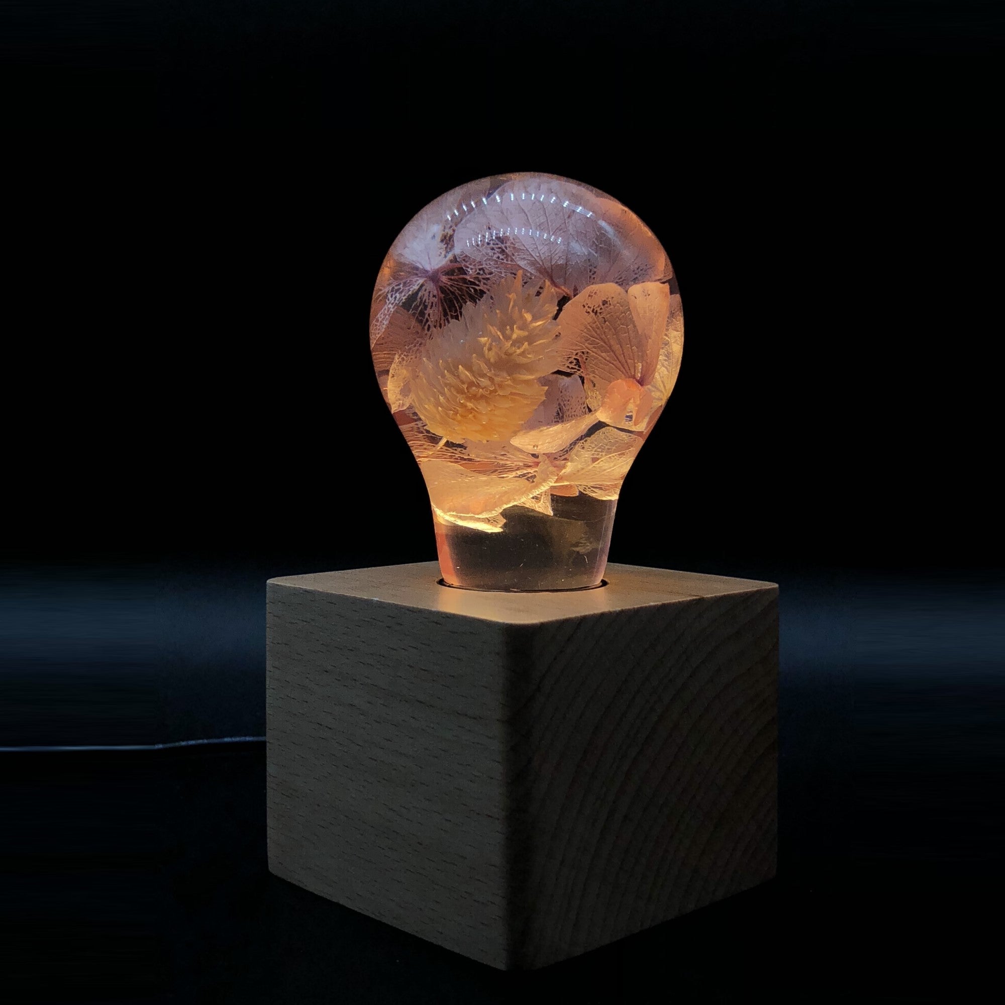 EP Light - Pink Hydrangea eco-resin bulb glowing softly on wooden base, unique handcrafted floral design.
