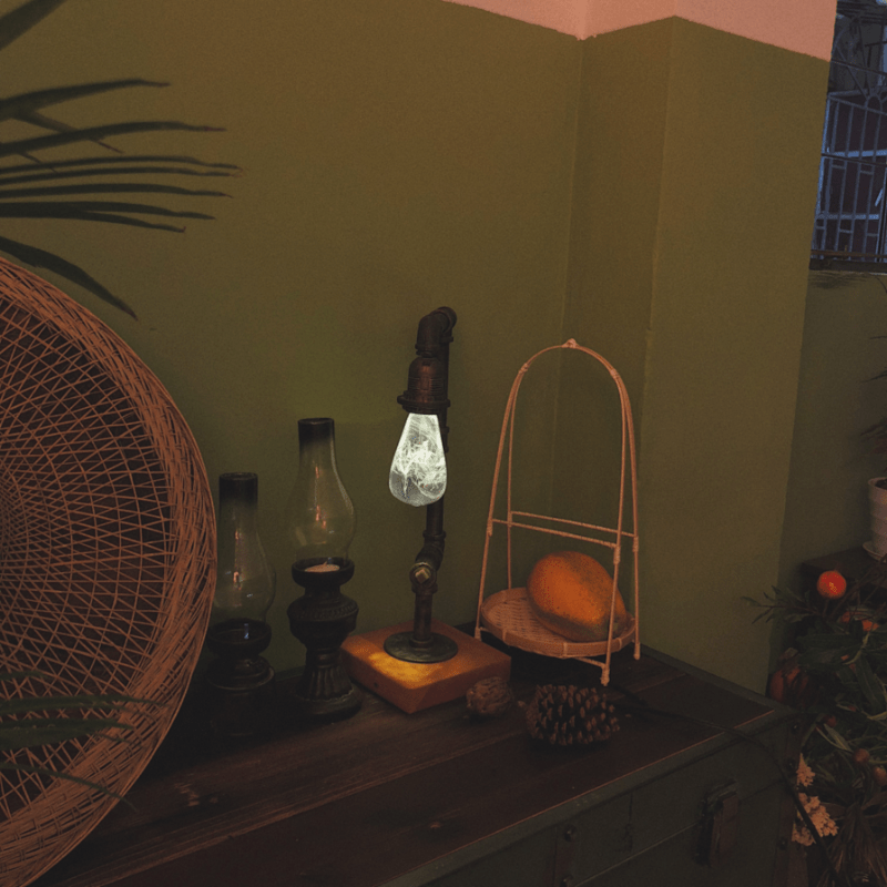 EP Light - Snow bulb glowing softly on a vintage pipe lamp, creating a warm, calming ambiance in a cozy room.