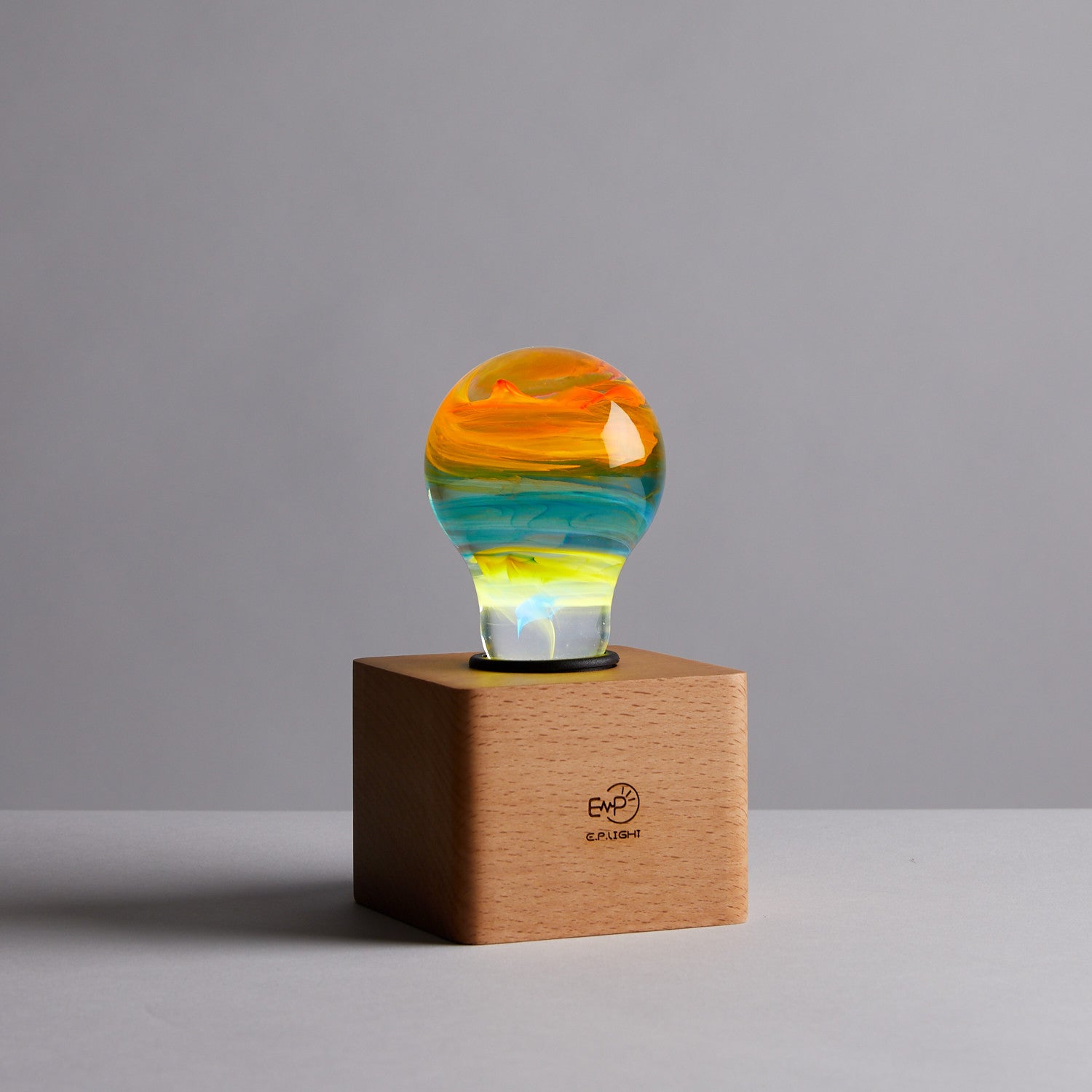 EP Light - Solar System bulb glowing with unique handcrafted colorful cosmos design on wooden base.