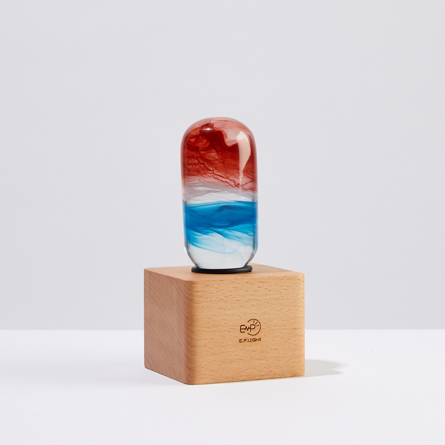 EP Light - Sunrise handcrafted resin LED bulb with vibrant red and blue sunrise colors on wooden base.