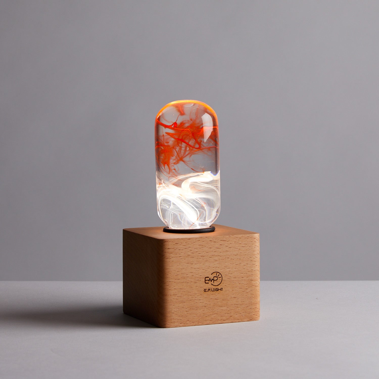 EP Light - Tango bulb with unique orange and white patterns, sleek eco-resin design on wooden base, vibrant and energy-saving.