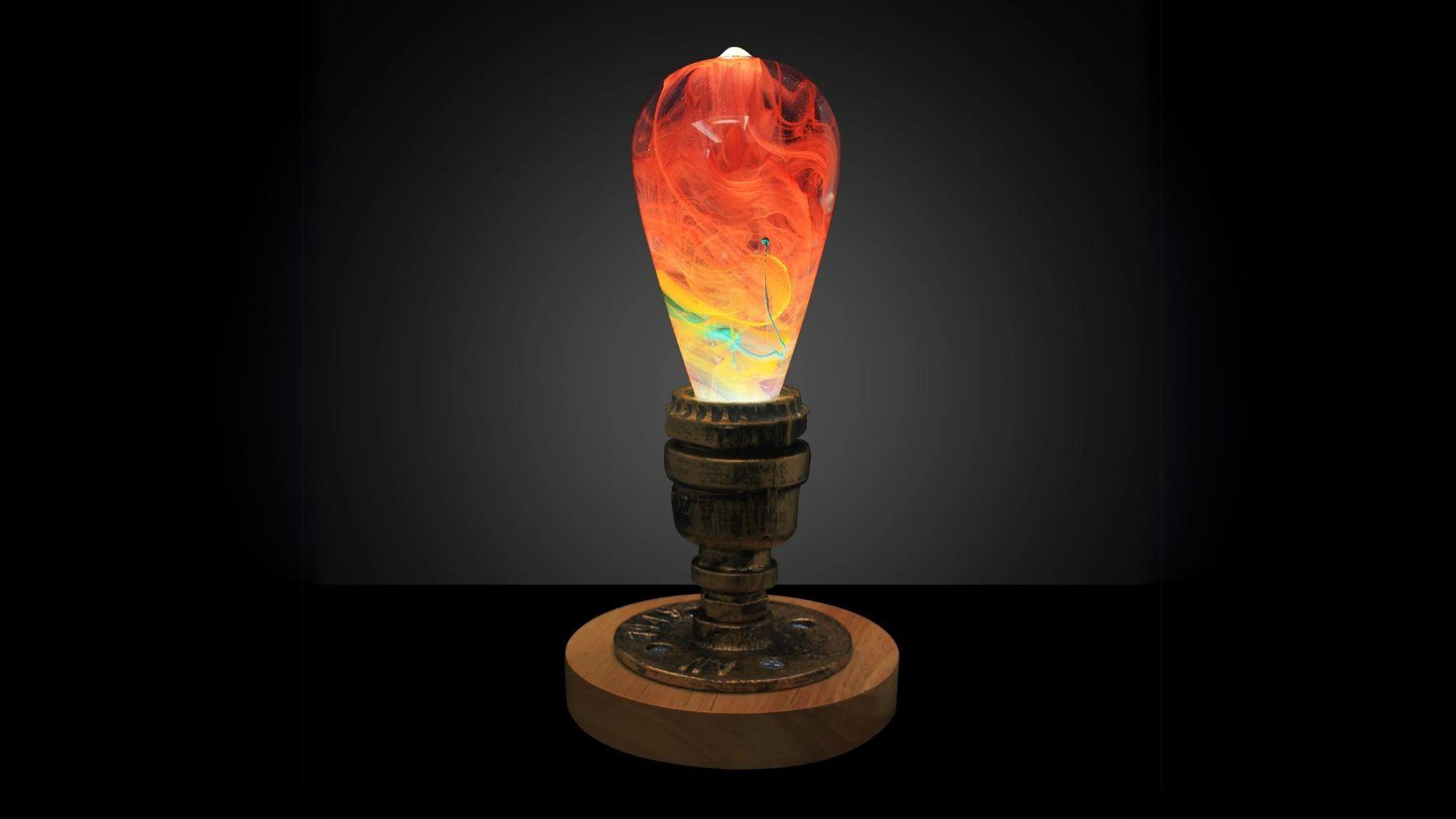 Artistic LED bulb lamp with vivid red and amber swirling patterns, set on a rustic metal and wood base against a dark background.