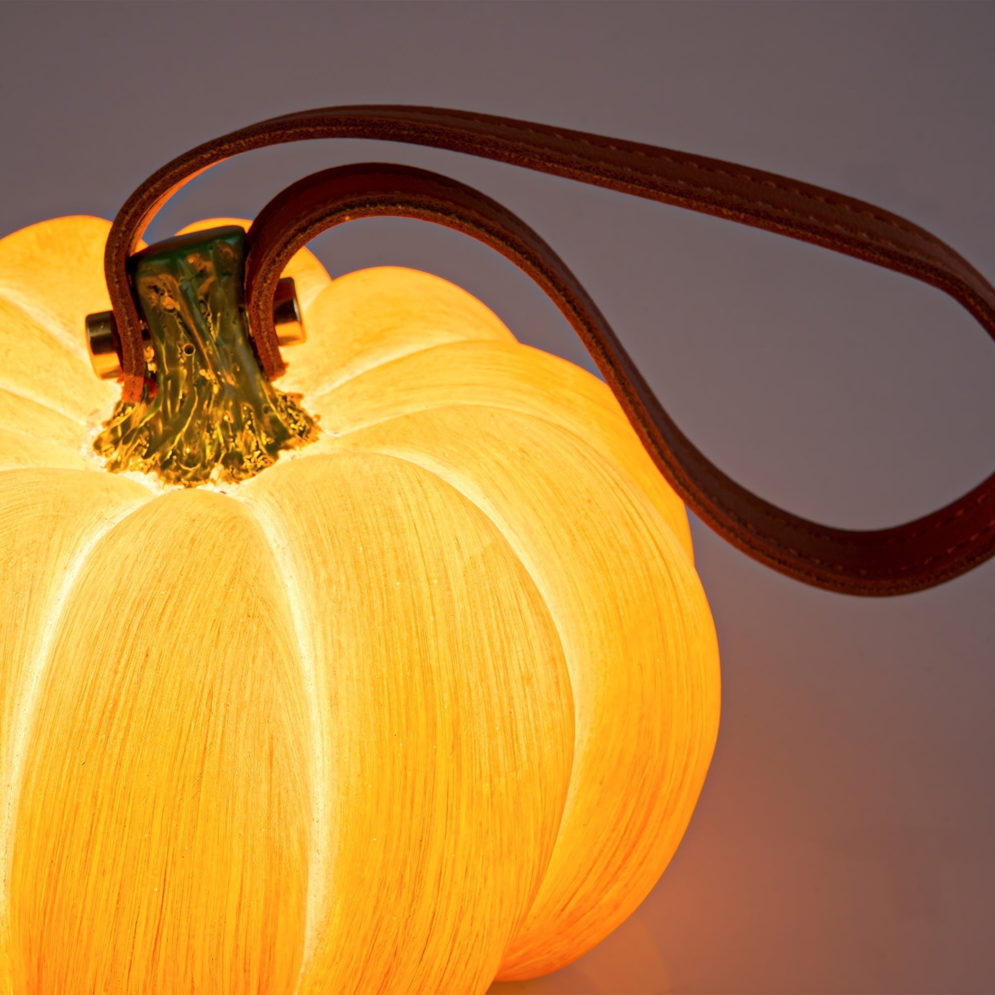 Indoor & Outdoor Pumpkin Lantern glowing warmly with a leather strap, perfect durable autumn decor for indoor and outdoor use.