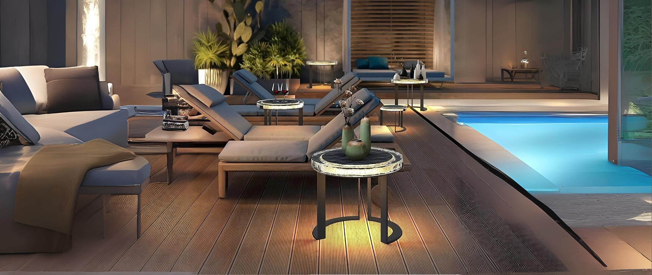 Modern outdoor lounge with LED-lit round side tables next to poolside recliners and decorative vases on wood decking.