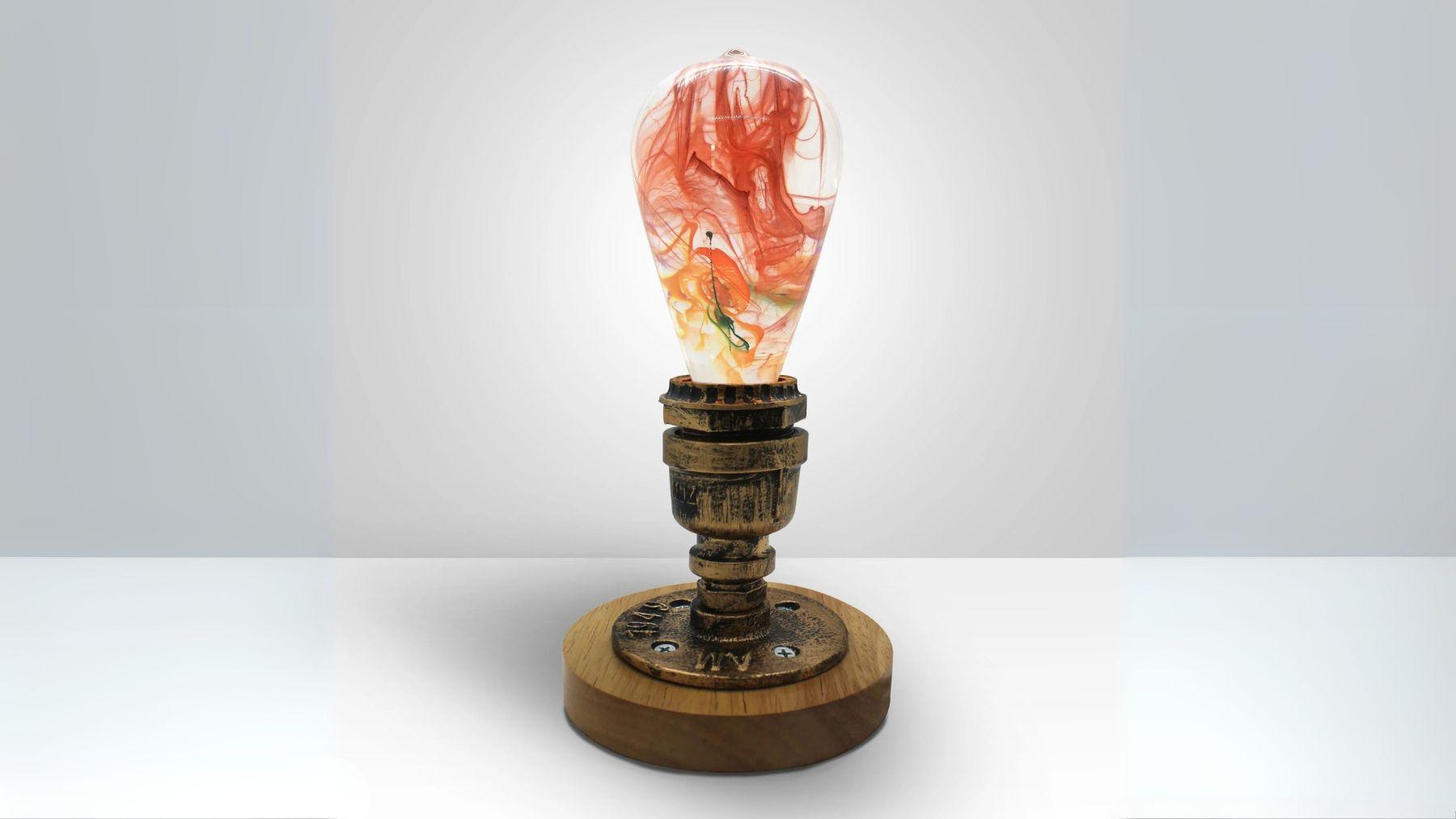 Decorative resin bulb lamp with swirling red, orange, and yellow patterns, mounted on a vintage industrial pipe base with round wooden support.