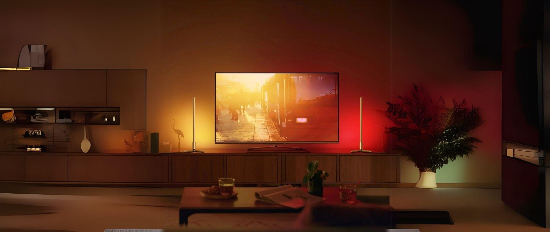 Living room with TV on a wooden console and two RGB light tubes on each side casting red and yellow ambient light.