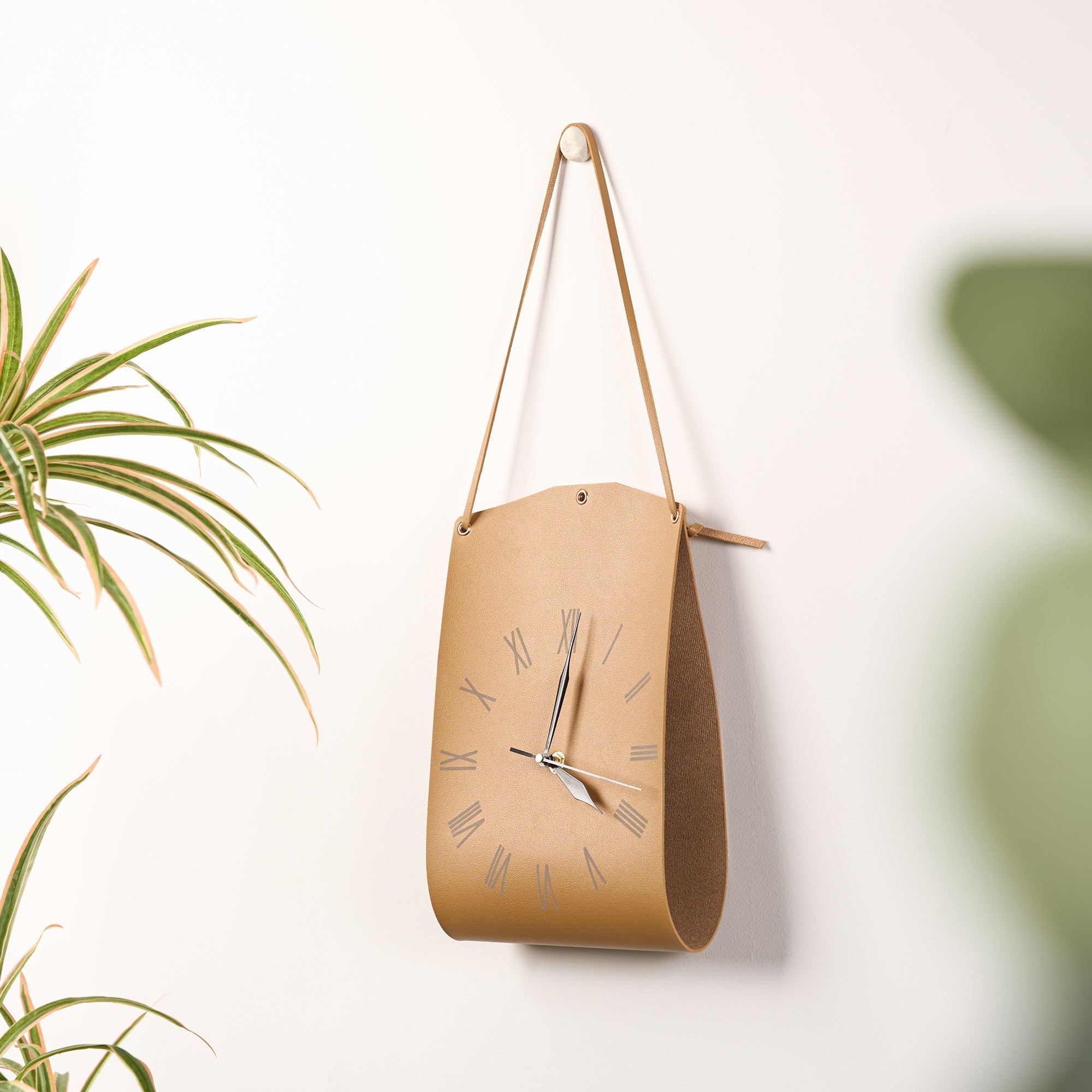 Roman Numerals Leather Wall Clock hanging on wall with sleek leather design and silent accurate timekeeping.
