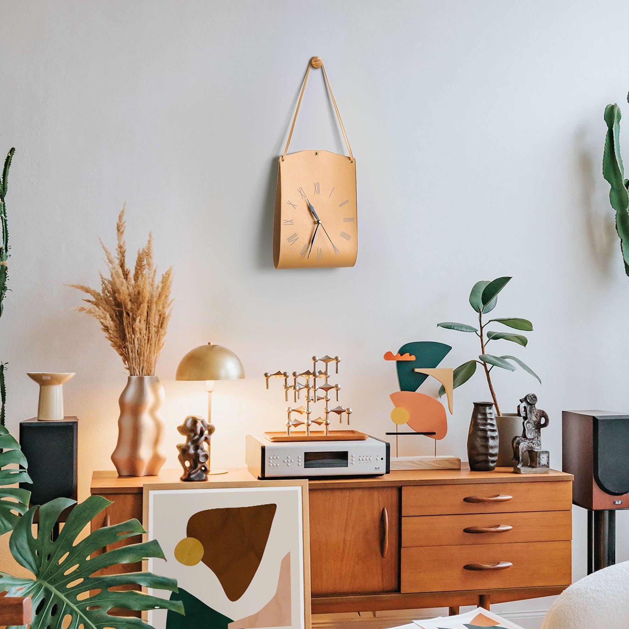 Roman Numerals Leather Wall Clock hanging on wall above stylish mid-century modern wooden cabinet with decor.