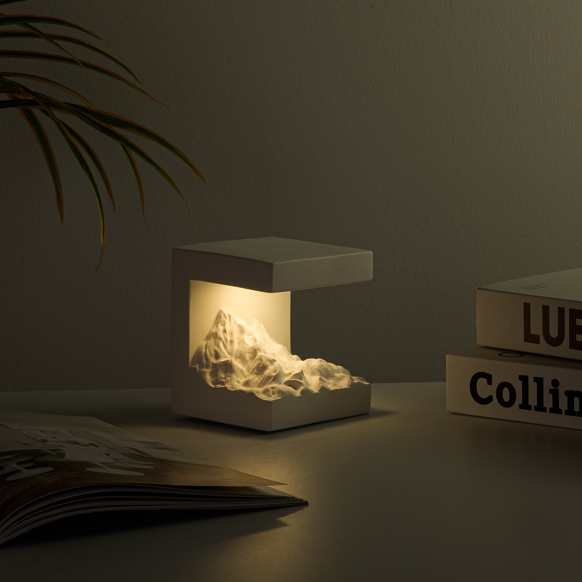 Snow Mountain Night Light & Diffuser Stone glowing softly with sculpted gypsum mountain design on a desk.