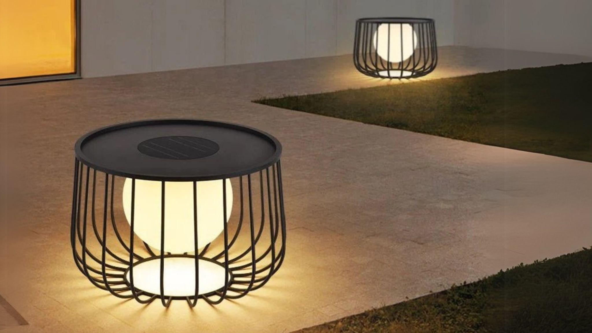 Solar Powered LED Outdoor Floor Lamp glowing on patio with sleek black cage design and soft ambient light at dusk.