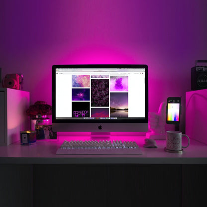 65 ft. Waterproof RGB Smart LED Strip Lights illuminating a desk setup with vibrant pink ambient lighting controlled via app.