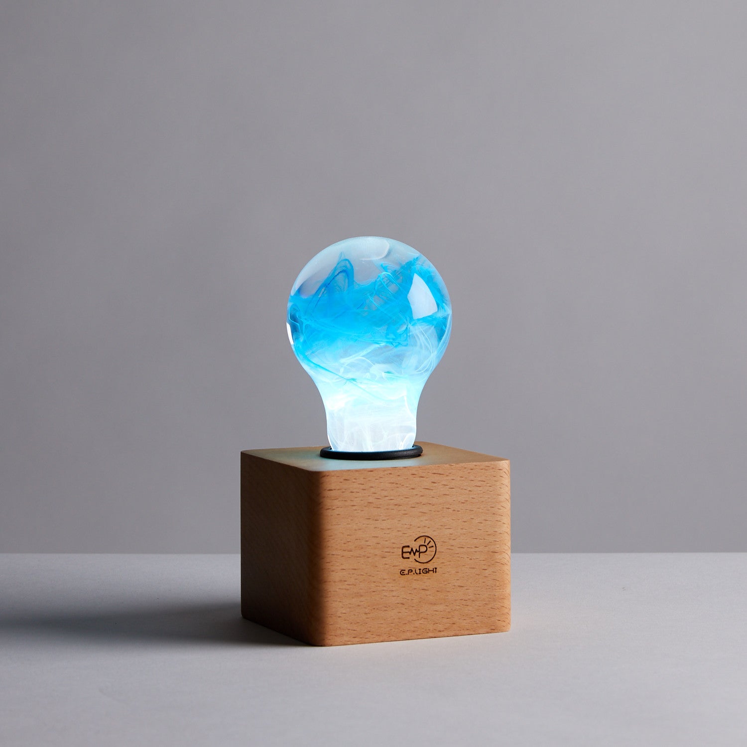 EP Light - Memory bulb glowing with unique blue swirl design on a vintage wooden base, handcrafted eco-resin light.